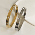 Gold and silver bangles with diamond-like stones on a light background