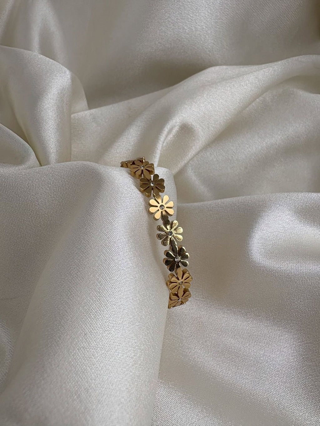 Gold bracelet with floral designs on a white fabric background