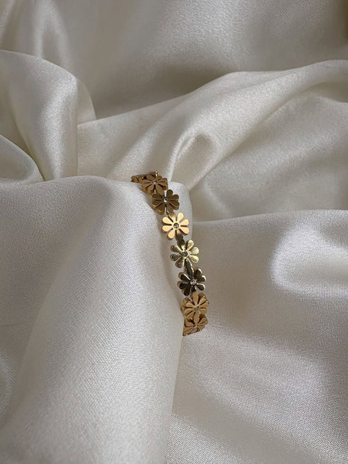 Gold bracelet with floral designs on a white fabric background