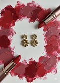 Gold flower-shaped earrings are placed in the center.