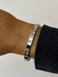 Silver bracelet with gemstones on a wrist against a neutral background
